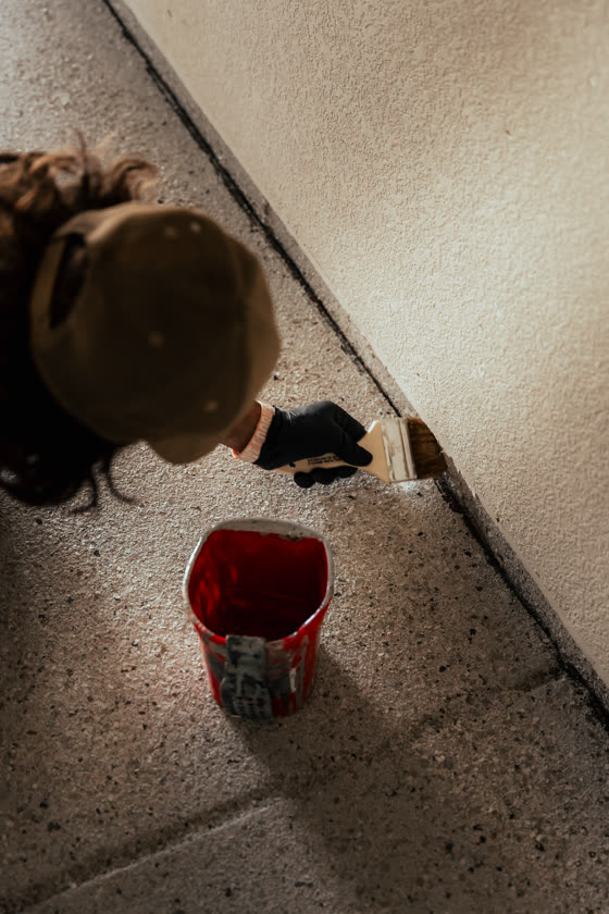 Contractor applying sealant along a wall base on a job site