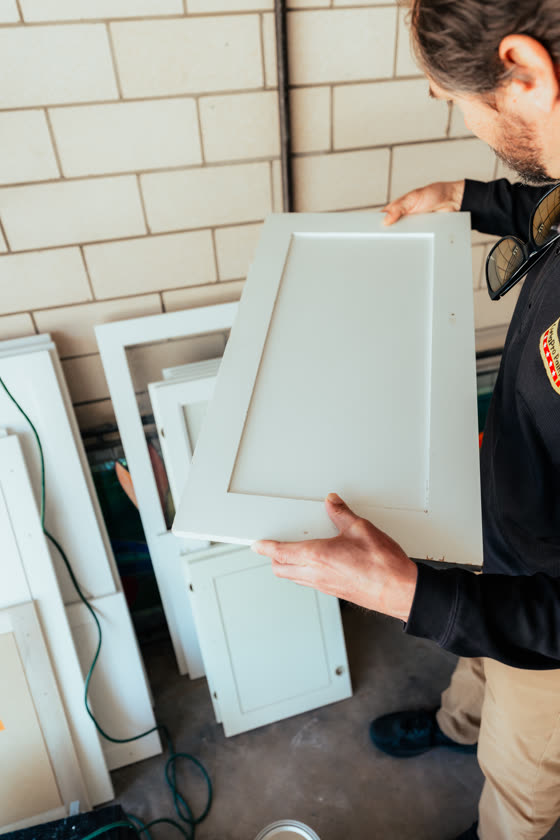 Installer carrying a white cabinet door on site