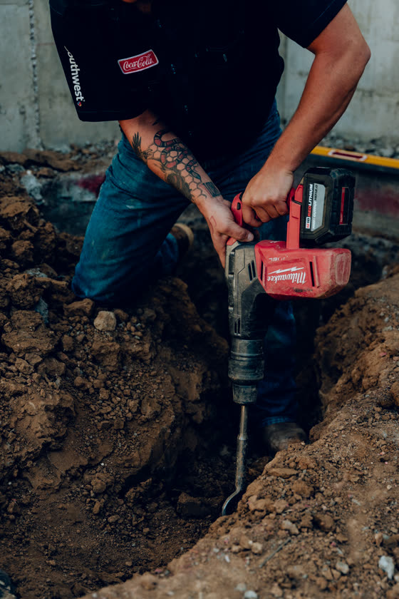 Worker breaking ground with a rotary hammer