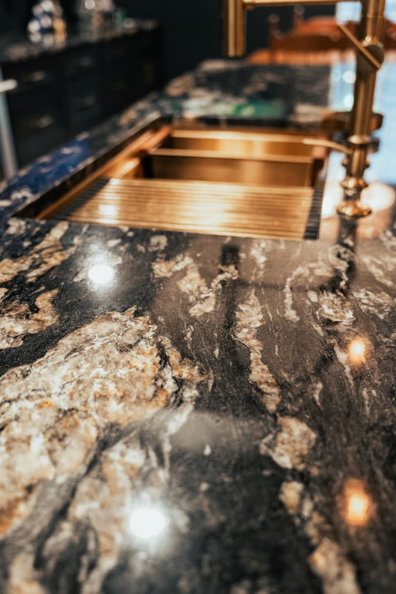 Granite countertop with a copper sink and brass fixtures